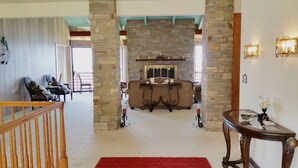 A cozy living room with a stone fireplace, a red rug, and a wooden staircase. - Arky's B&B (Smith River)