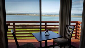 A balcony with a table and chairs overlooking a beach. - Arky's B&B (Smith River)
