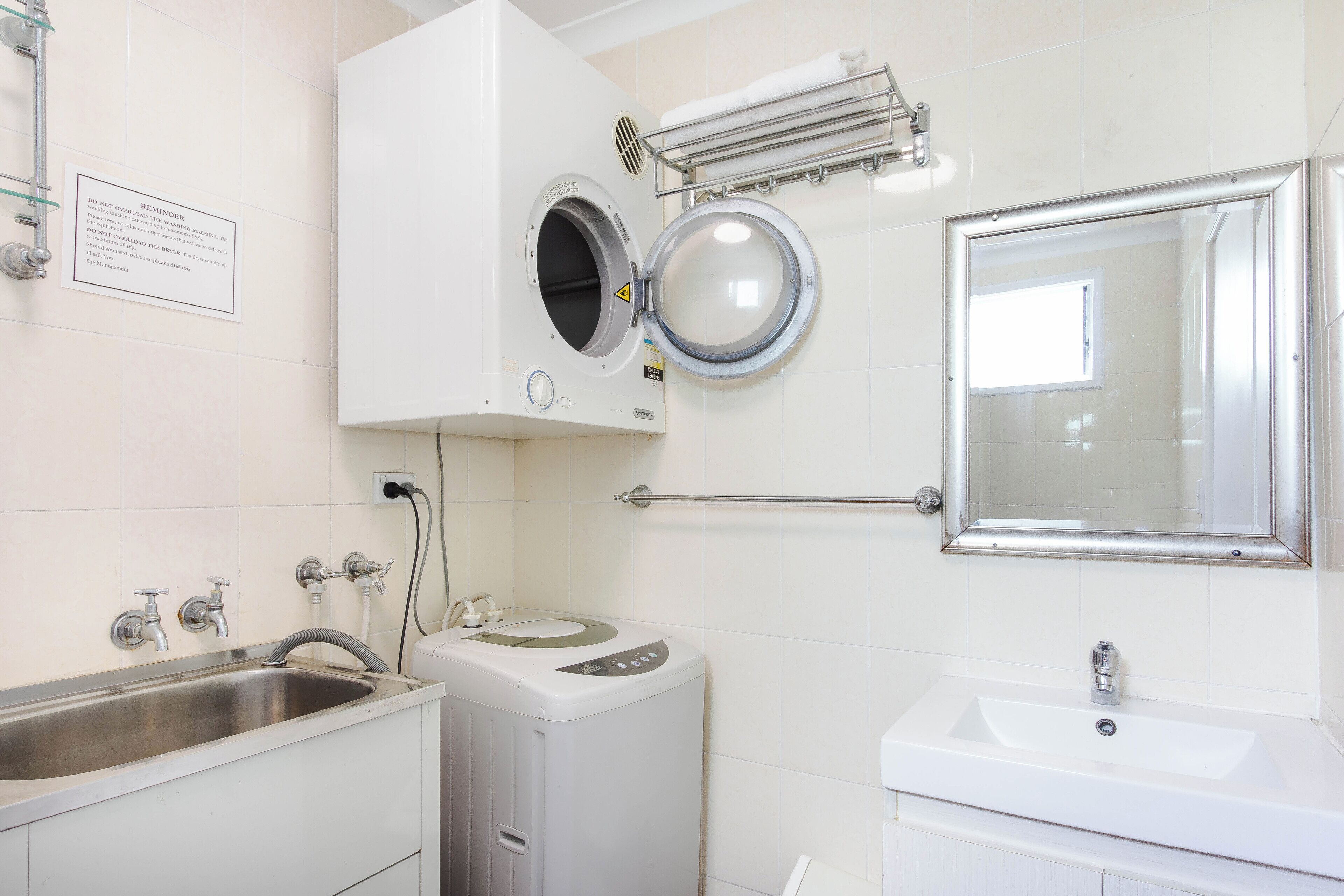 Un baño con lavadora, lavabo y espejo.