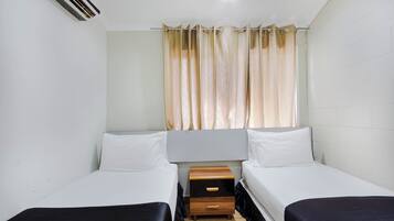 Une chambre double avec deux lits, une table de chevet en bois et une fenêtre avec des rideaux.
