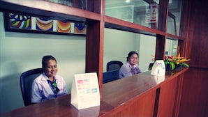 A reception desk with a sign, a computer, and a plant. - Citi Serviced Apartments - Korobosea (Port Moresby)