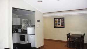 A compact living space with a kitchenette, a dining area, and a black leather sofa. - Citi Serviced Apartments - Korobosea (Port Moresby)