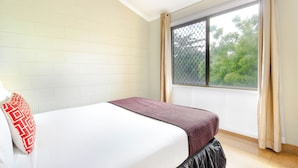 A bedroom with a bed, a window with curtains, and a view of trees outside. - Citi Serviced Apartments - Korobosea (Port Moresby)