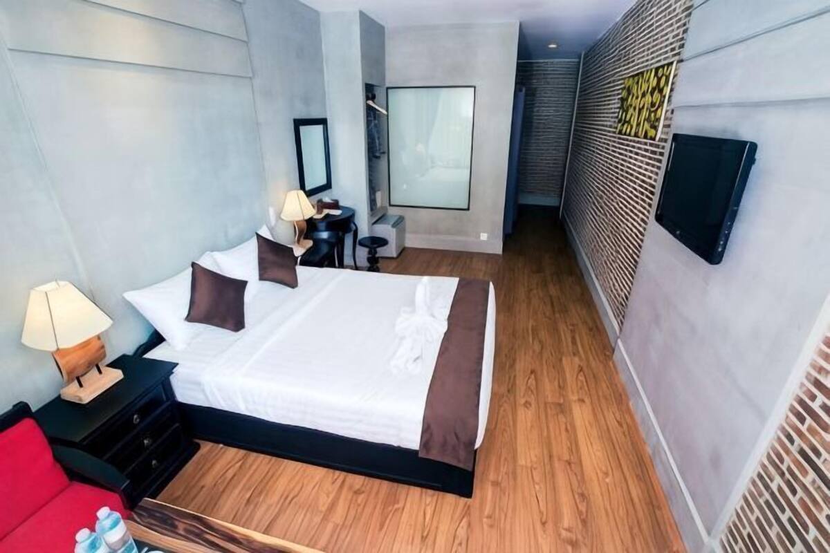 Una habitación de hotel moderna con una cama grande, mesitas de noche, un escritorio y una silla.