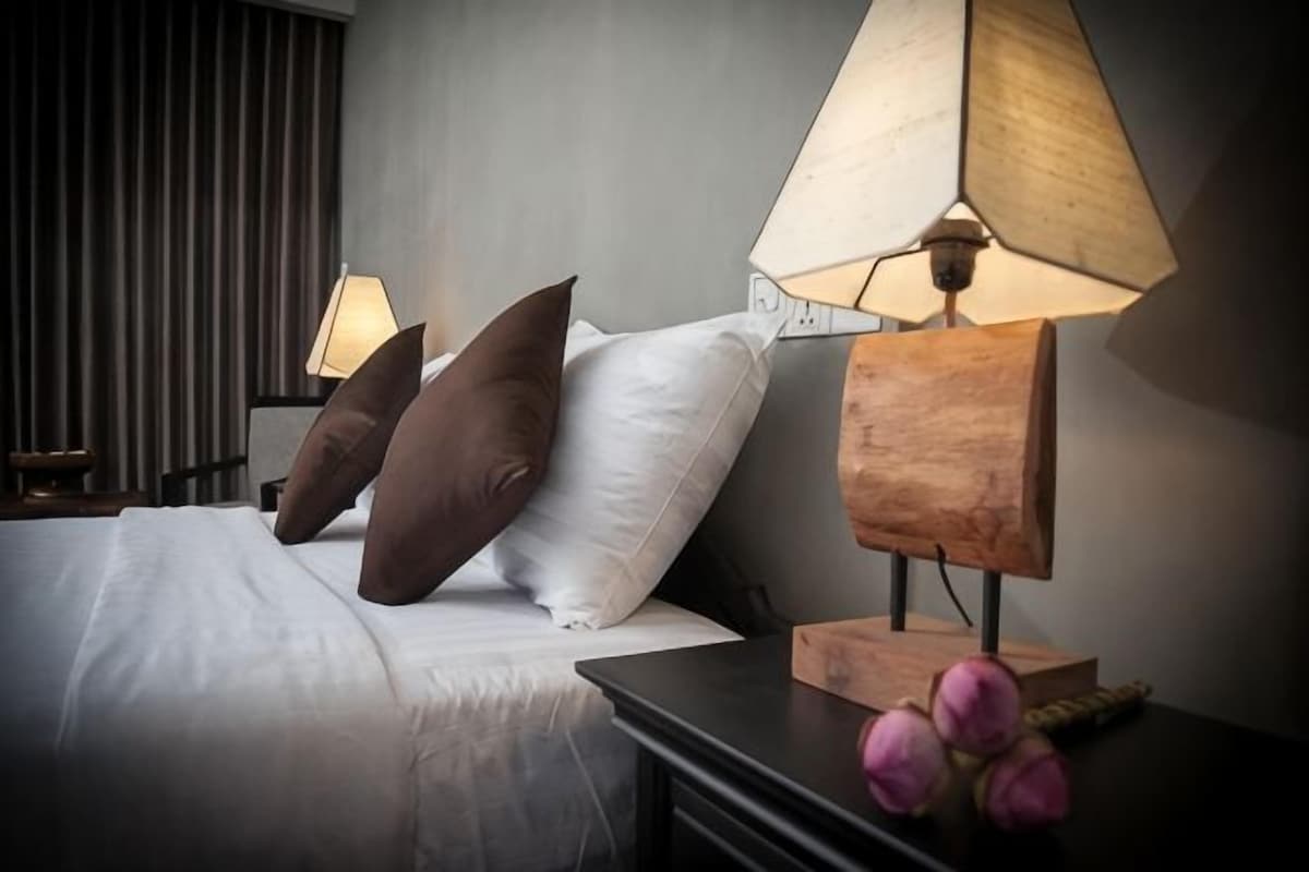A hotel room with a bed, two bedside lamps, and a nightstand with decorative items.