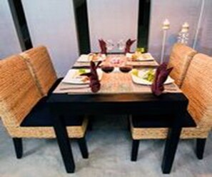 A dining table with two chairs, a placemat, and a candle. - Vacation Boutique Hotel (Phnom Penh)