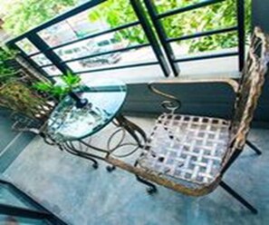 A small outdoor seating area with a glass table and a metal chair. - Vacation Boutique Hotel (Phnom Penh)