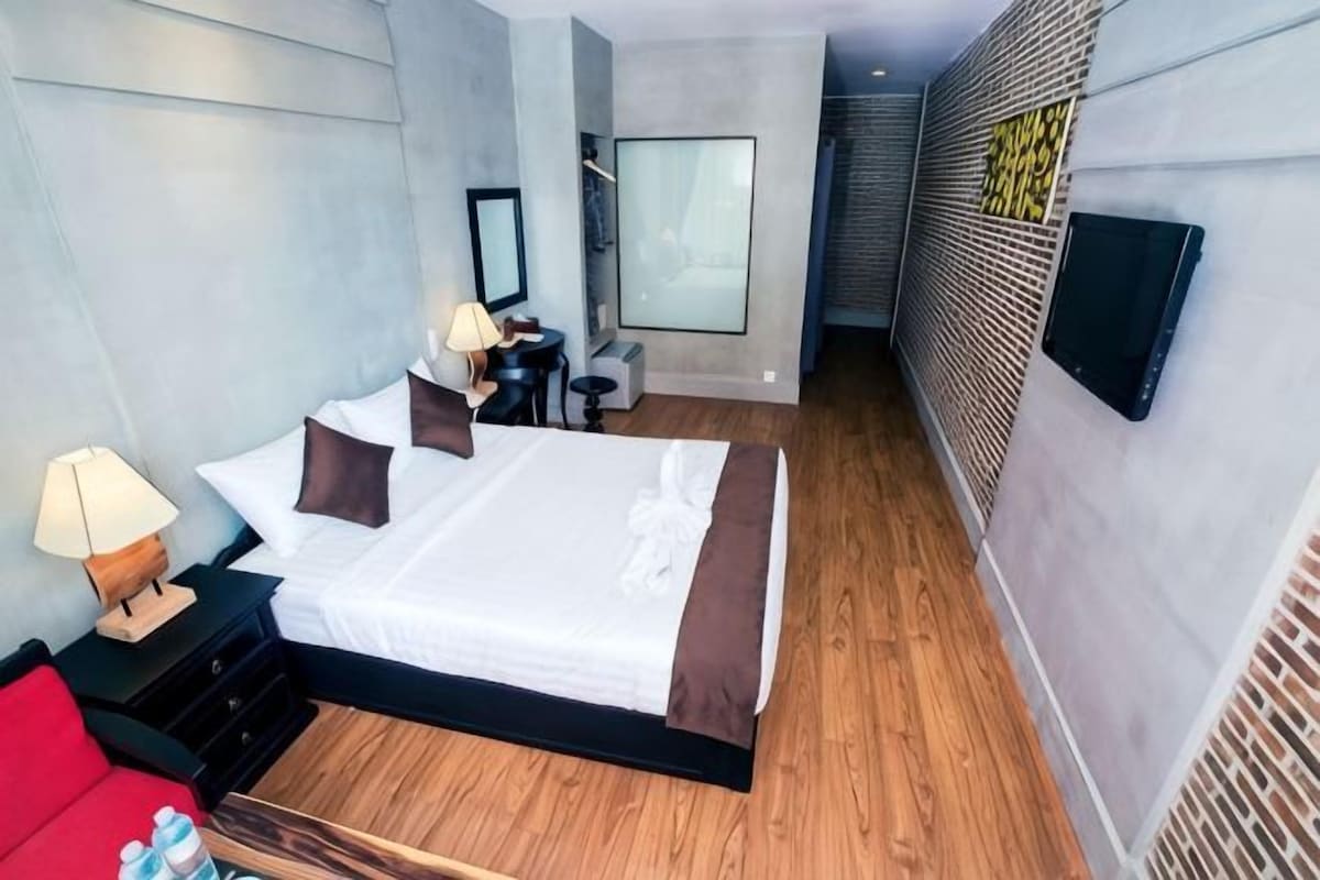 Una habitación de hotel moderna con una cama grande, mesitas de noche, un escritorio y una silla.