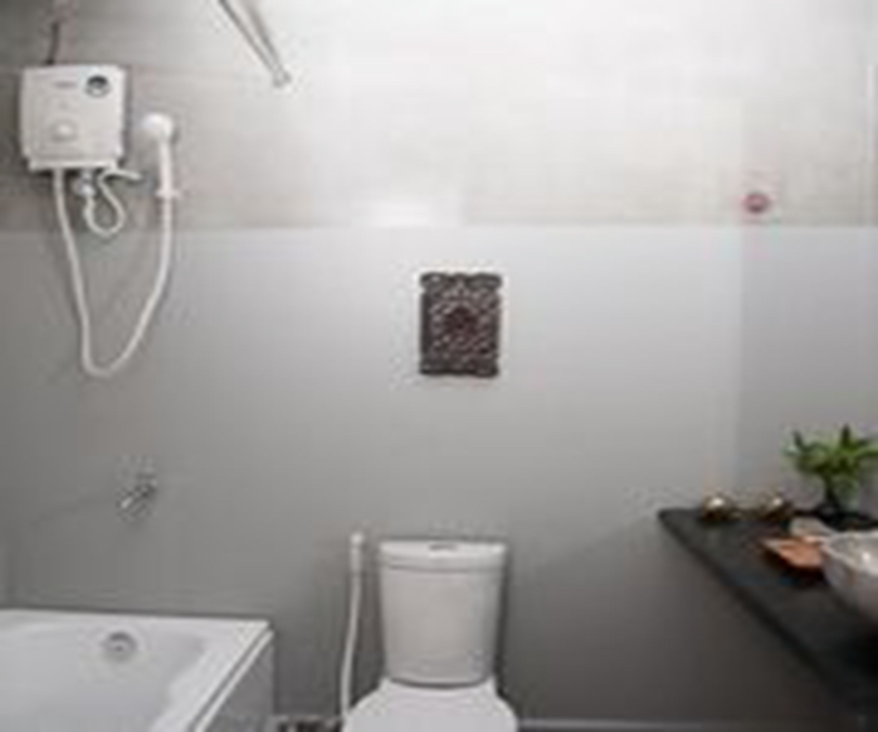 A bathroom with a toilet, a shower, and a sink.