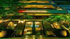 Een hotel met meerdere verdiepingen, modern van stijl, met een opvallende entree met glazen deuren en een goed verlichte gevel.