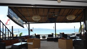 Un área de estar al aire libre con mobiliario de mimbre y vistas al mar.