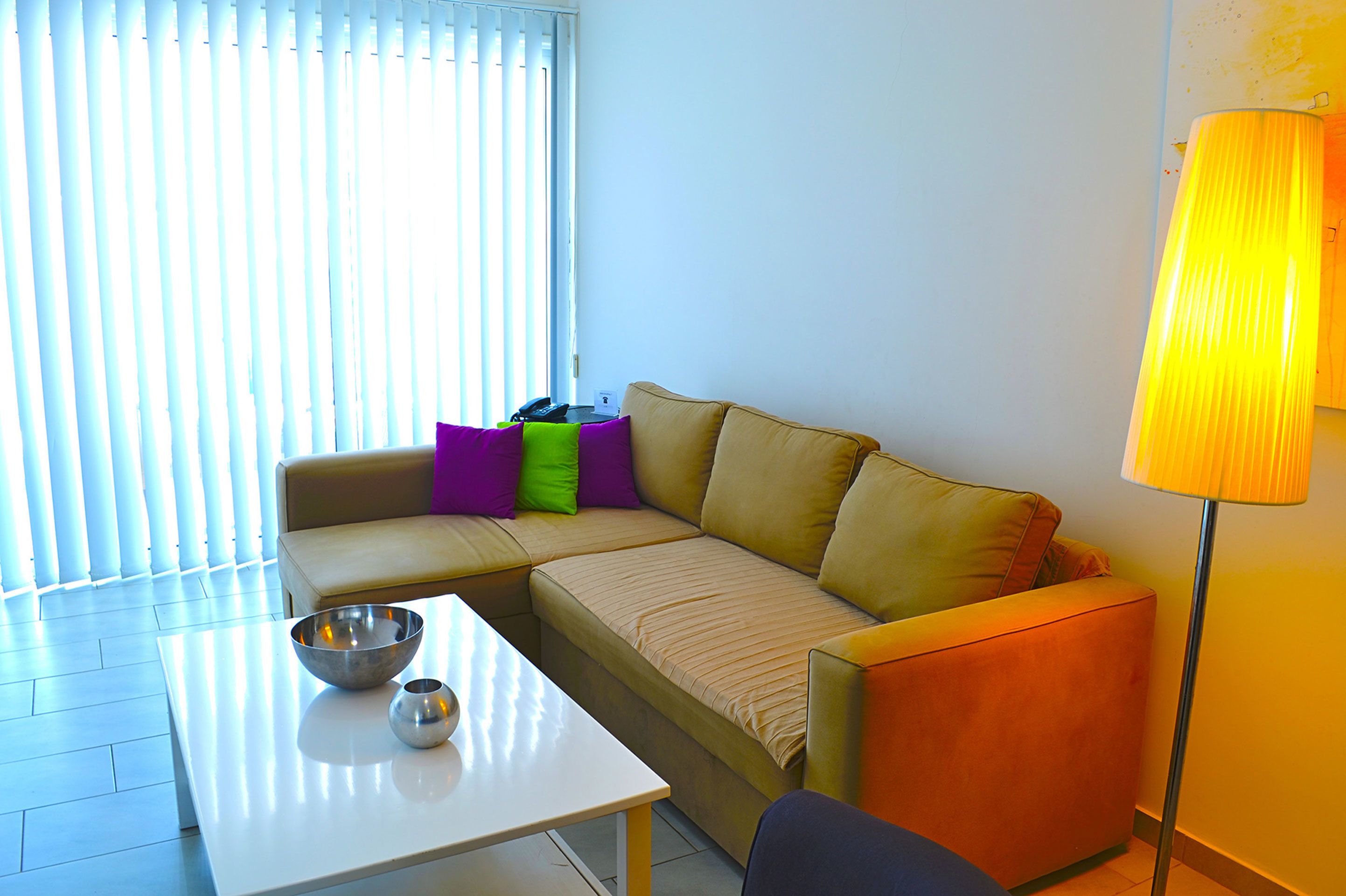 A modern living room with a beige sectional sofa, a white coffee table, and a floor lamp.