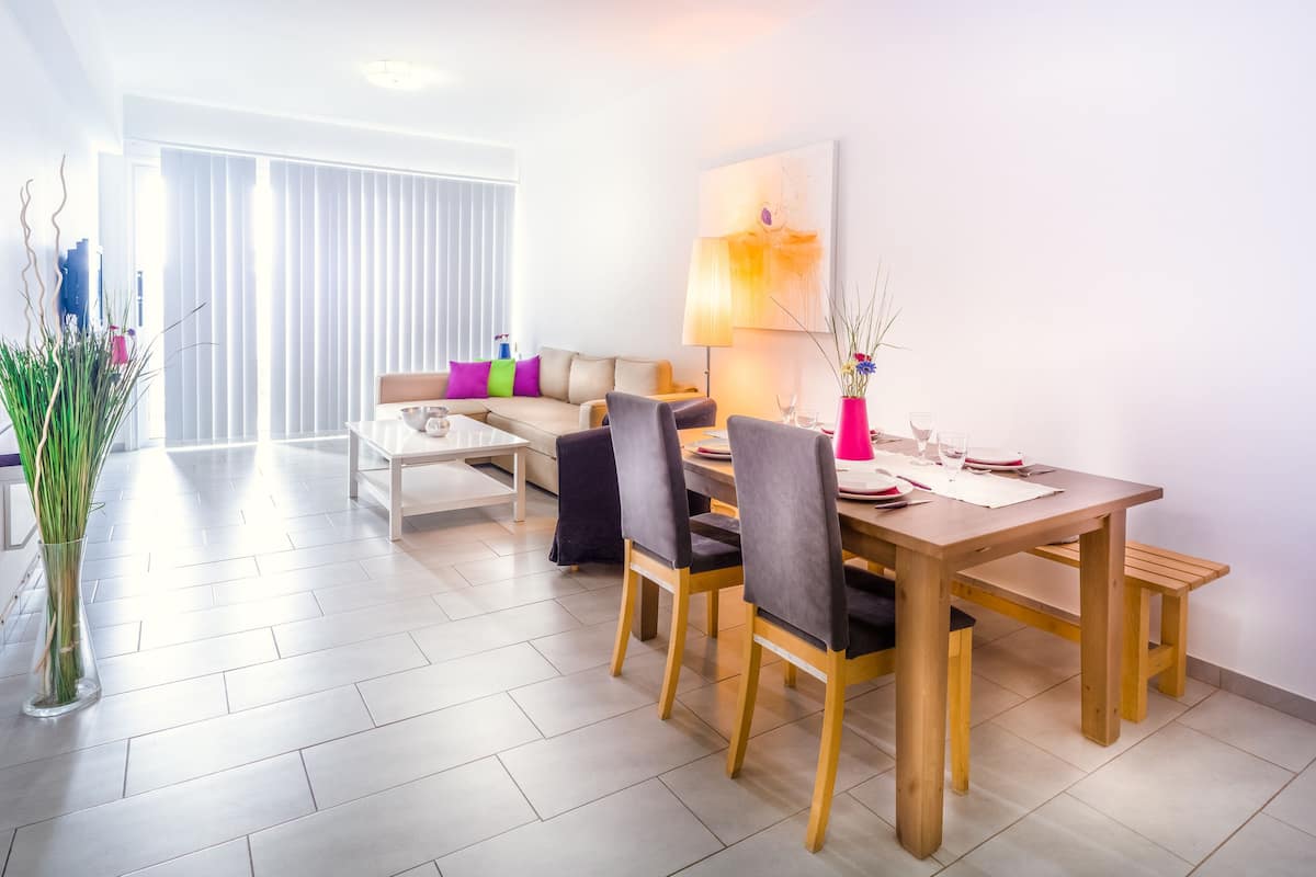 Un soggiorno moderno con zona pranzo, che include un divano, un tavolino da caffè e un tavolo da pranzo in legno con sedie.