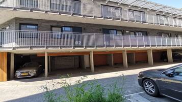 A multi-story hotel with a covered parking area, a staircase, and a balcony with railings.