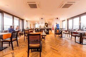 A spacious dining area with wooden flooring, large windows, and modern furniture. - Tower Hotel (Aalst)