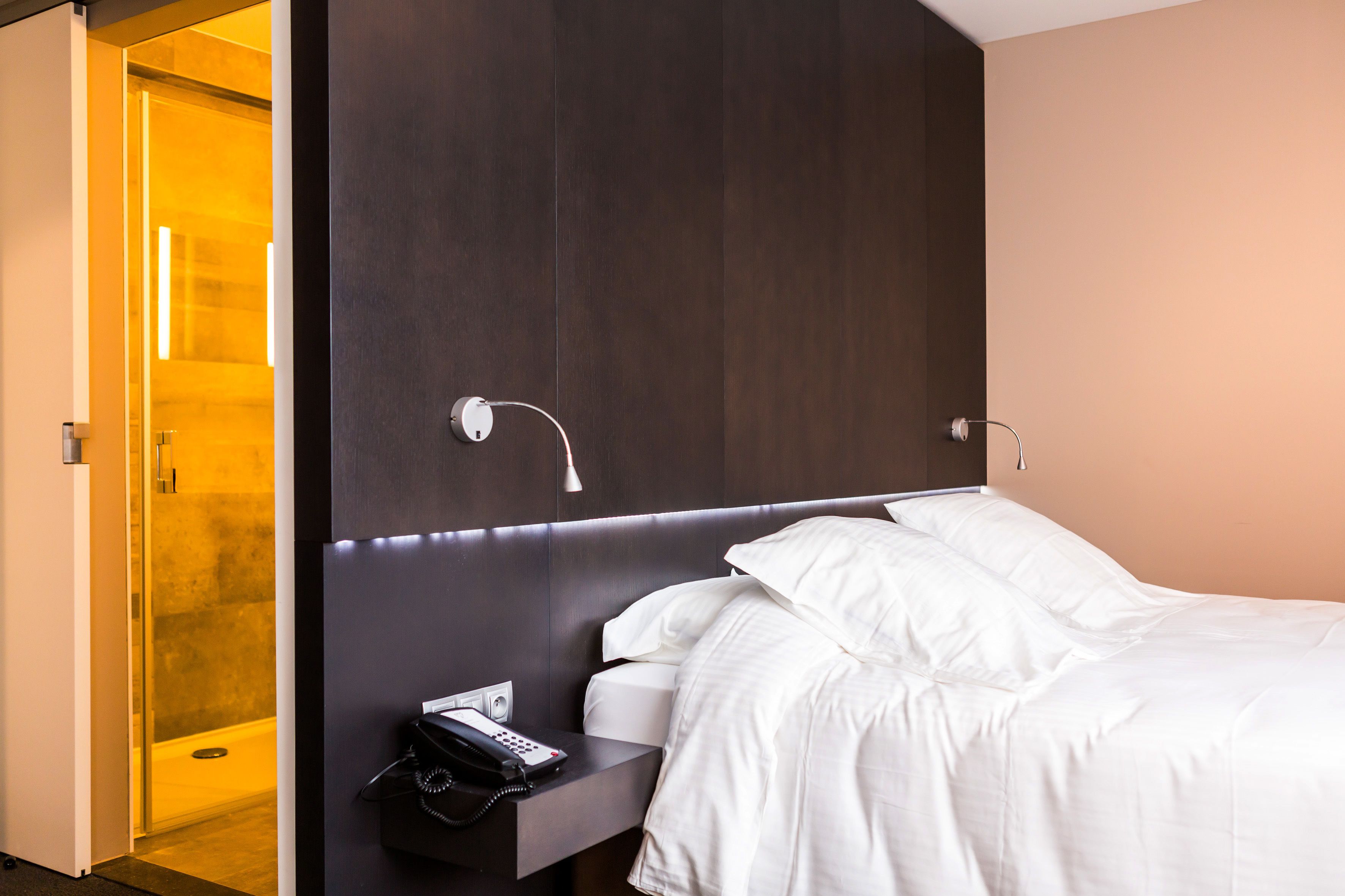 A hotel room with a bed, bedside table, and a phone.