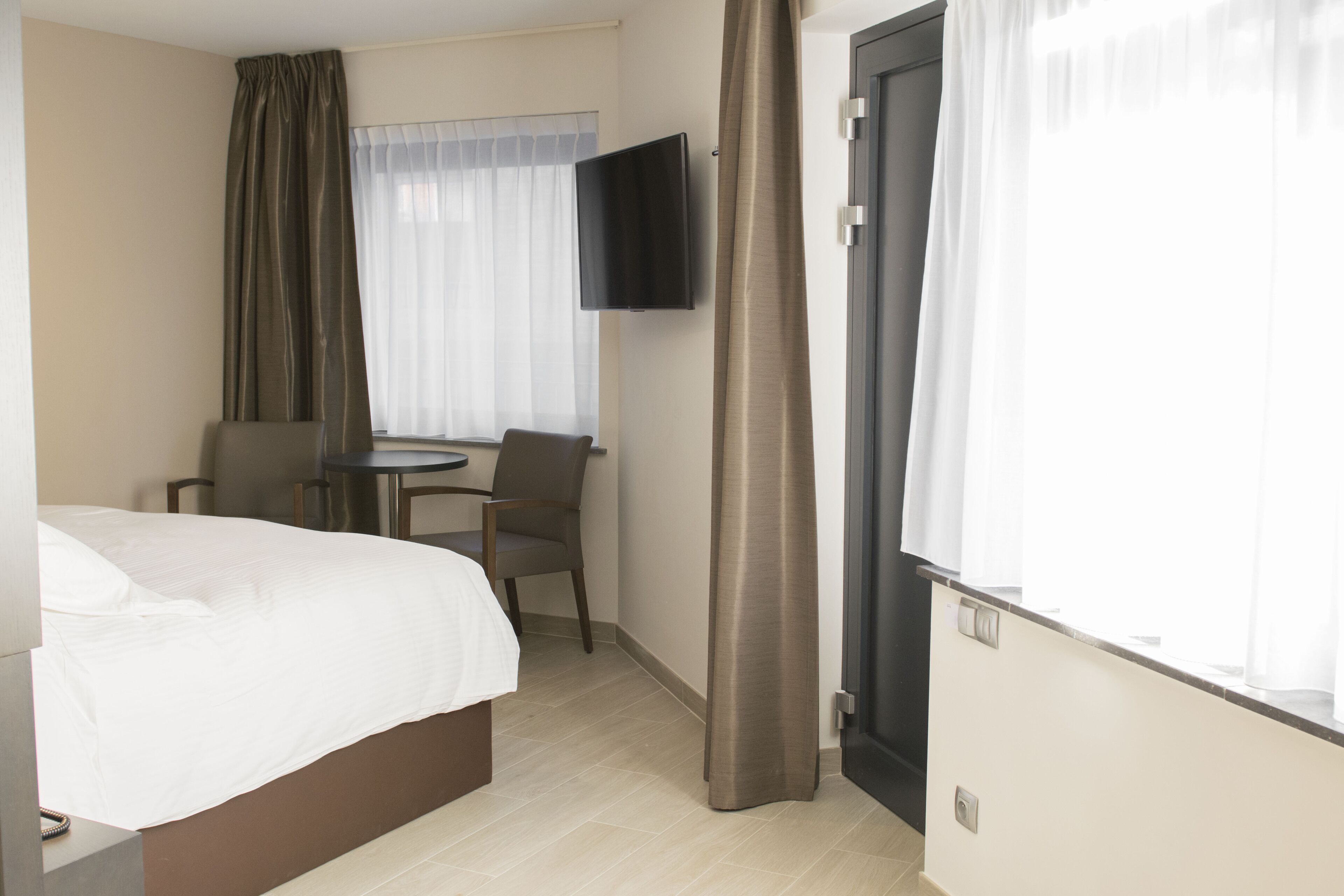 Una habitación de hotel con una cama, un escritorio, una silla, un televisor y una puerta.