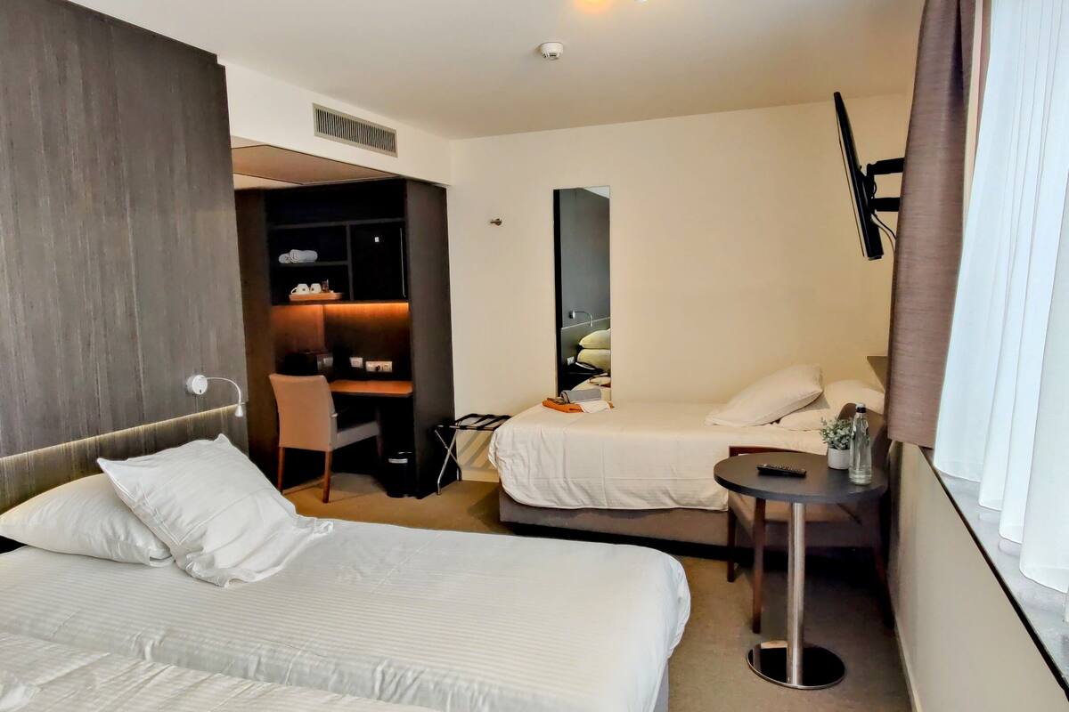 Una habitación de hotel con dos camas, un escritorio, una silla, una mesita y un televisor.
