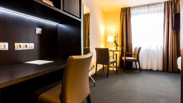 Een hotelkamer met een bureau, twee stoelen, een lamp en een televisie.