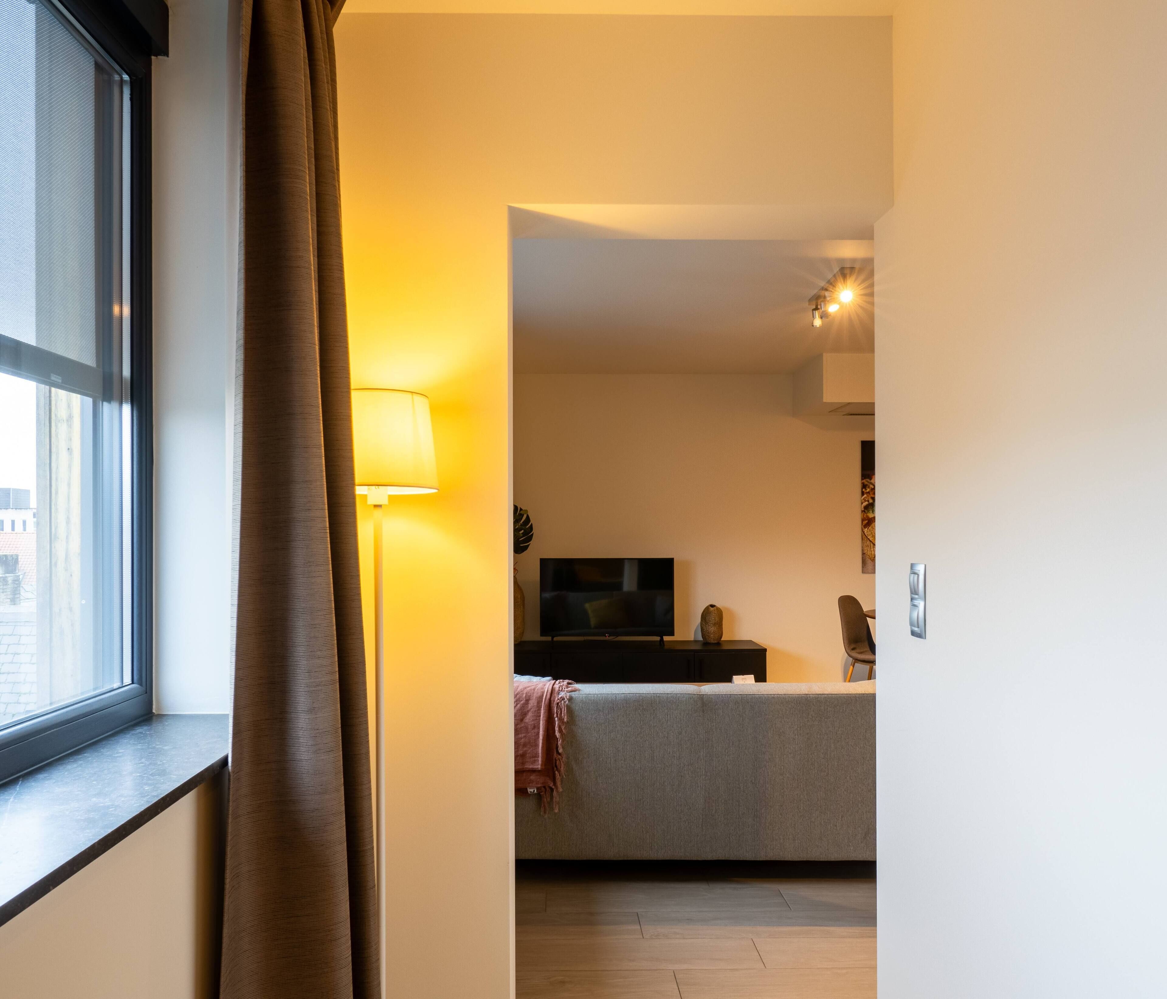 Una sala de estar moderna con un sofá, un televisor y una lámpara.