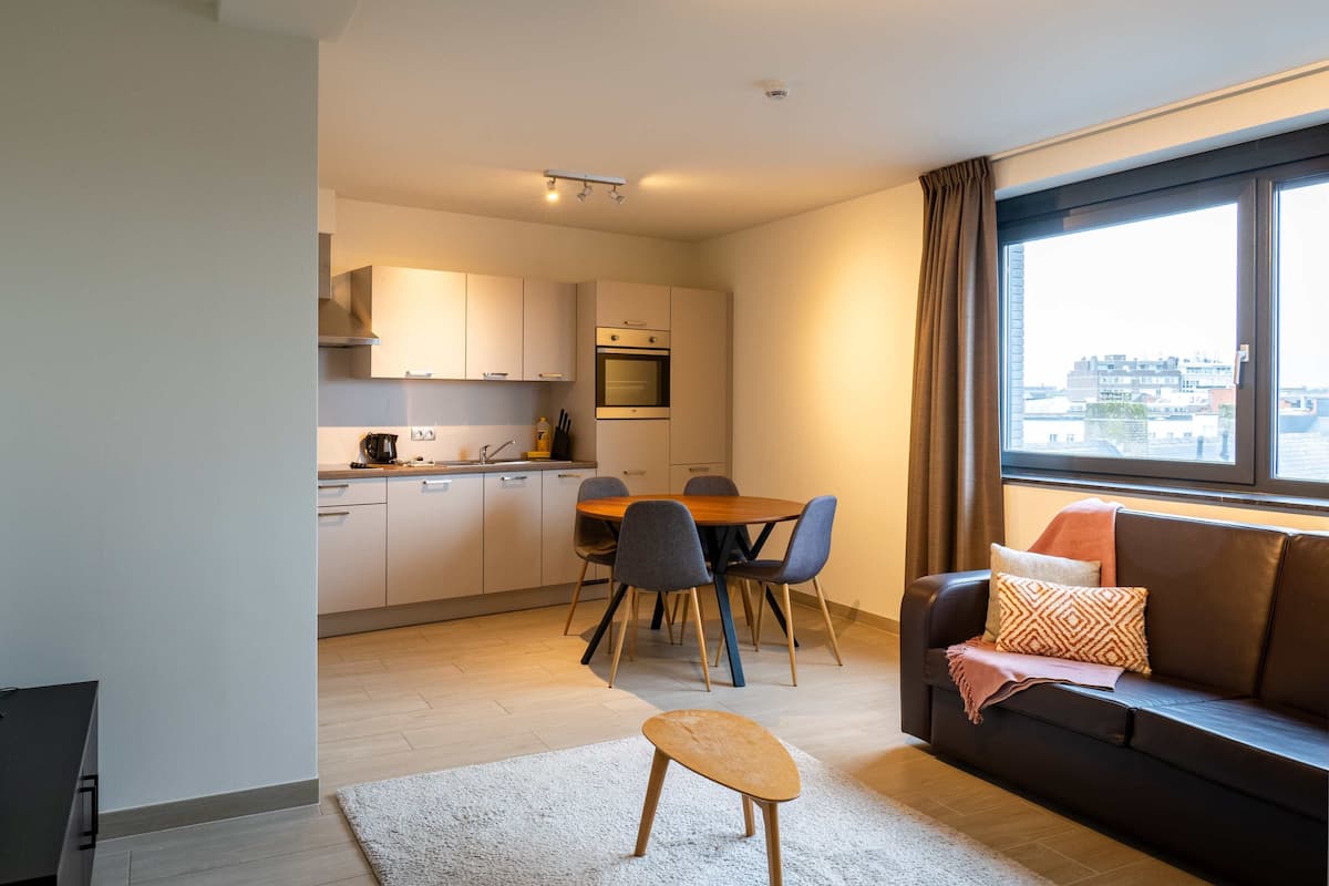 Un apartamento moderno con cocina, comedor y una zona de estar acogedora con un gran ventanal.