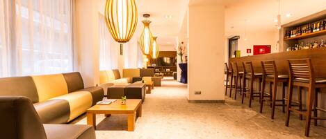 Un hall de hotel con una zona de bar, sofás y una mesa de centro.