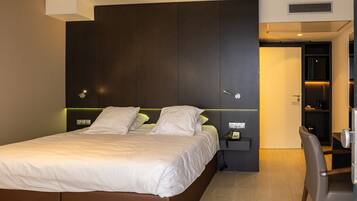 A modern hotel room with a large bed, bedside tables, a desk, and a chair.