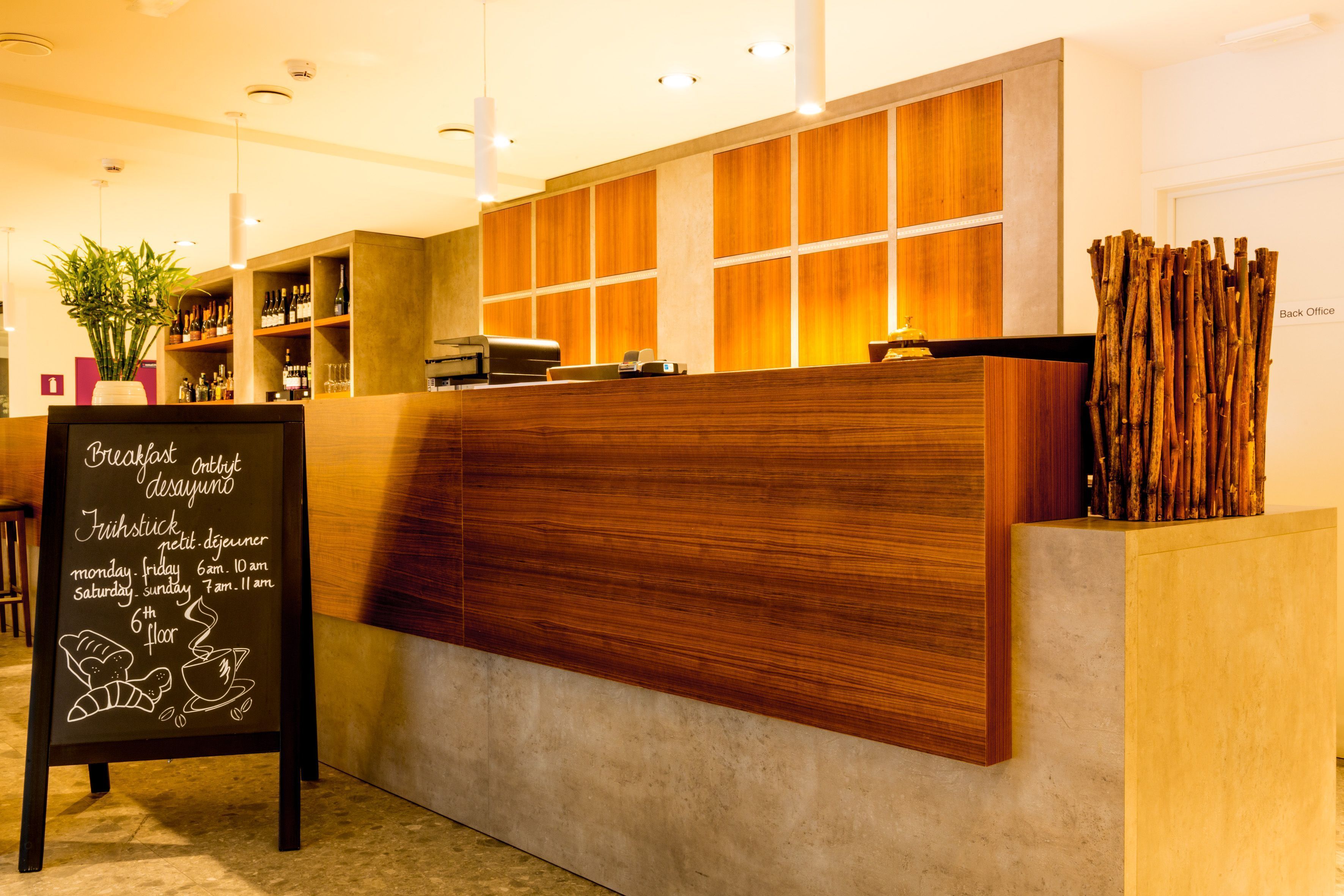 A reception desk with a chalkboard sign detailing breakfast hours and location.
