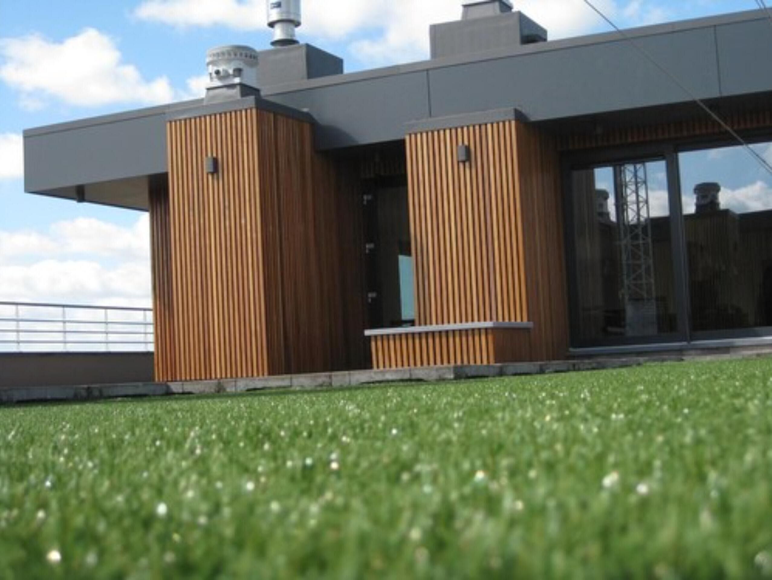 Een modern gebouw met een plat dak, grote ramen en houten lambrisering.