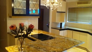 A kitchen with granite countertops, a built-in stove, and a vase with red flowers on the island. - Villa La Vida- Self-Catering House (Umhlanga)