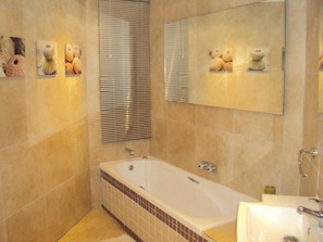 A bathroom with a bathtub, a sink, and a mirror.