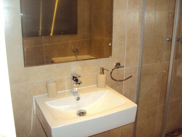 A bathroom with a white sink, a mirror above it, and a towel rack.