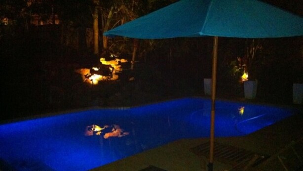 A swimming pool with a blue hue, surrounded by a deck area with lounge chairs and a table. - Villa La Vida- Self-Catering House (Umhlanga)