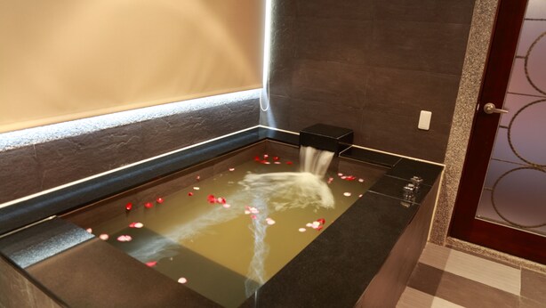 A spa area with a water feature, a small black box, and rose petals on the floor. - Spring Breeze Motel (Hualien City)