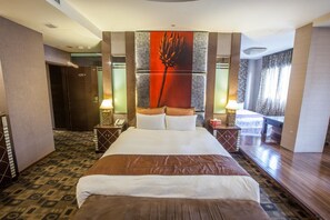 A hotel room with a large bed, two bedside tables with lamps, a large window with curtains, and a door to the left. - Spring Breeze Motel (Hualien City)