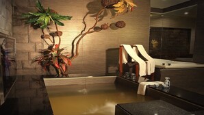 A modern bathroom with a stone wall, a wooden bench, a large plant, and a bathtub. - Spring Breeze Motel (Hualien City)