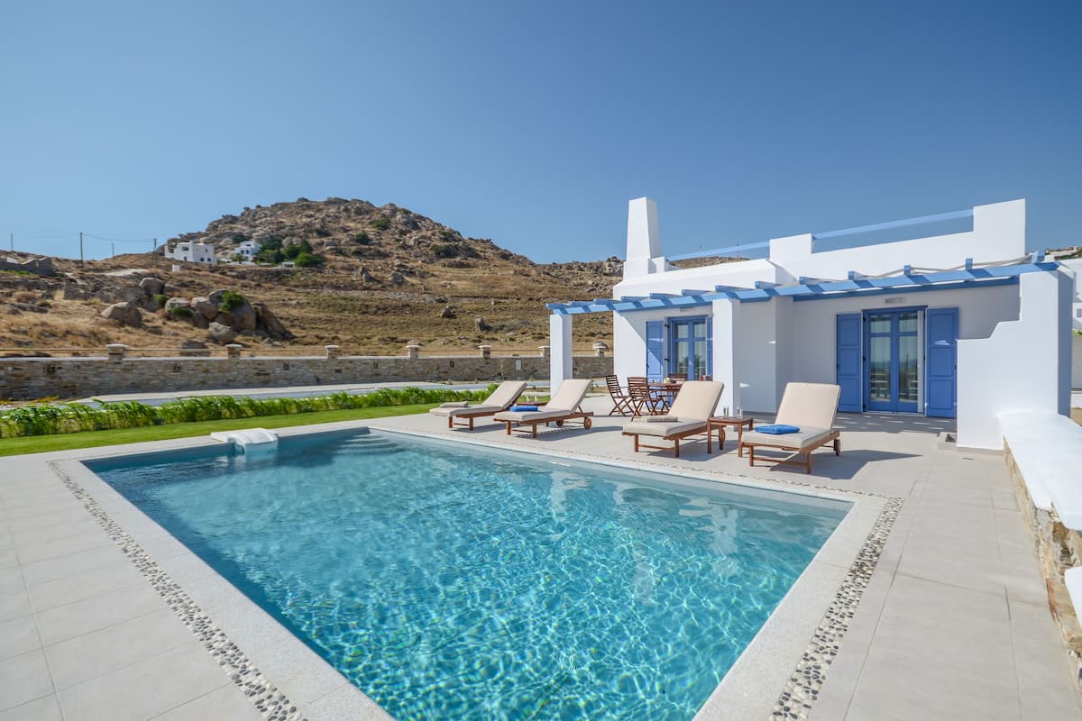 A swimming pool with lounge chairs and a building with a blue door and windows.