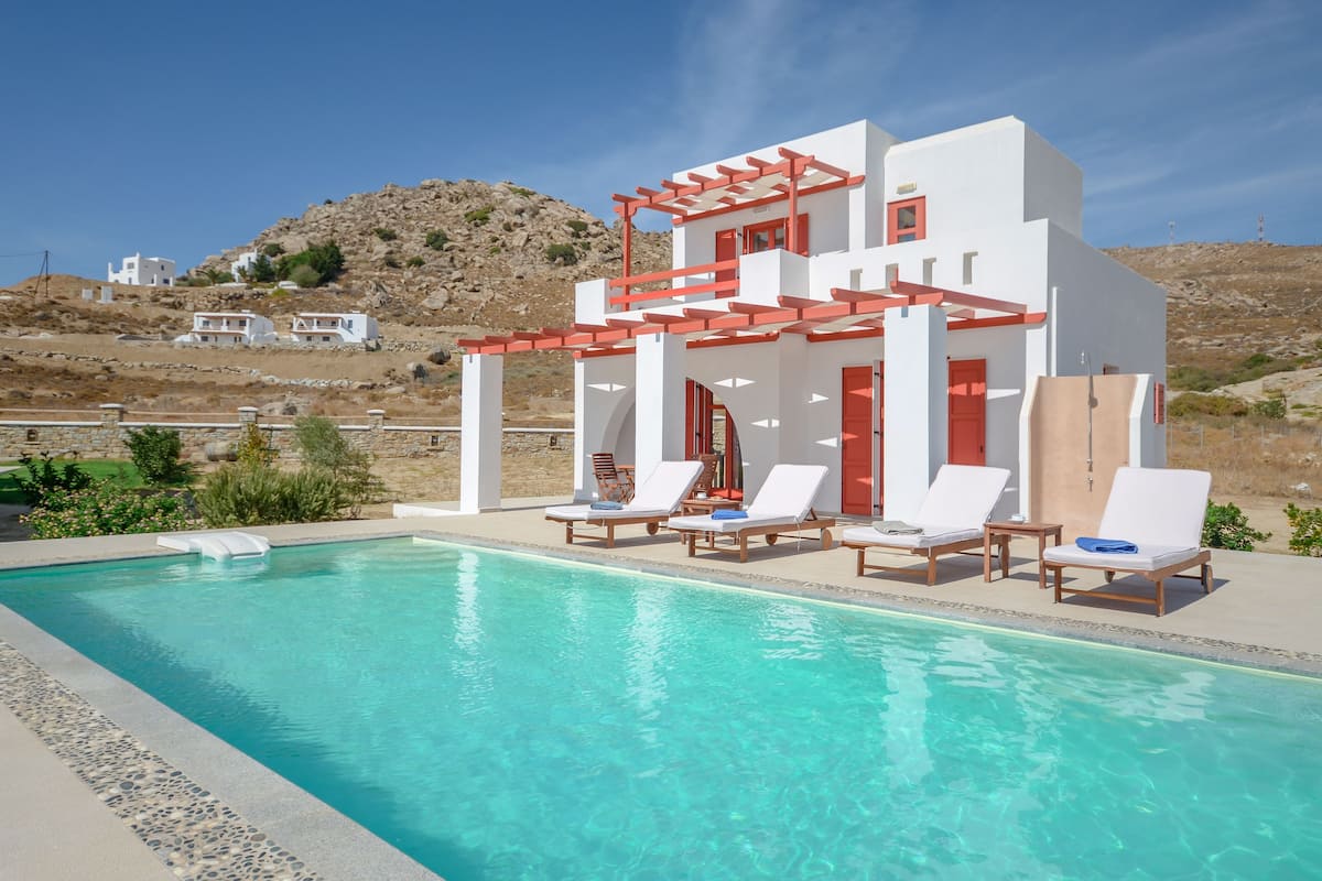 A modern pool area with white and red architecture, including a pergola and lounge chairs.