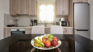 Una cocina moderna con armarios de madera, un refrigerador de acero inoxidable y una mesa de comedor con frutero.