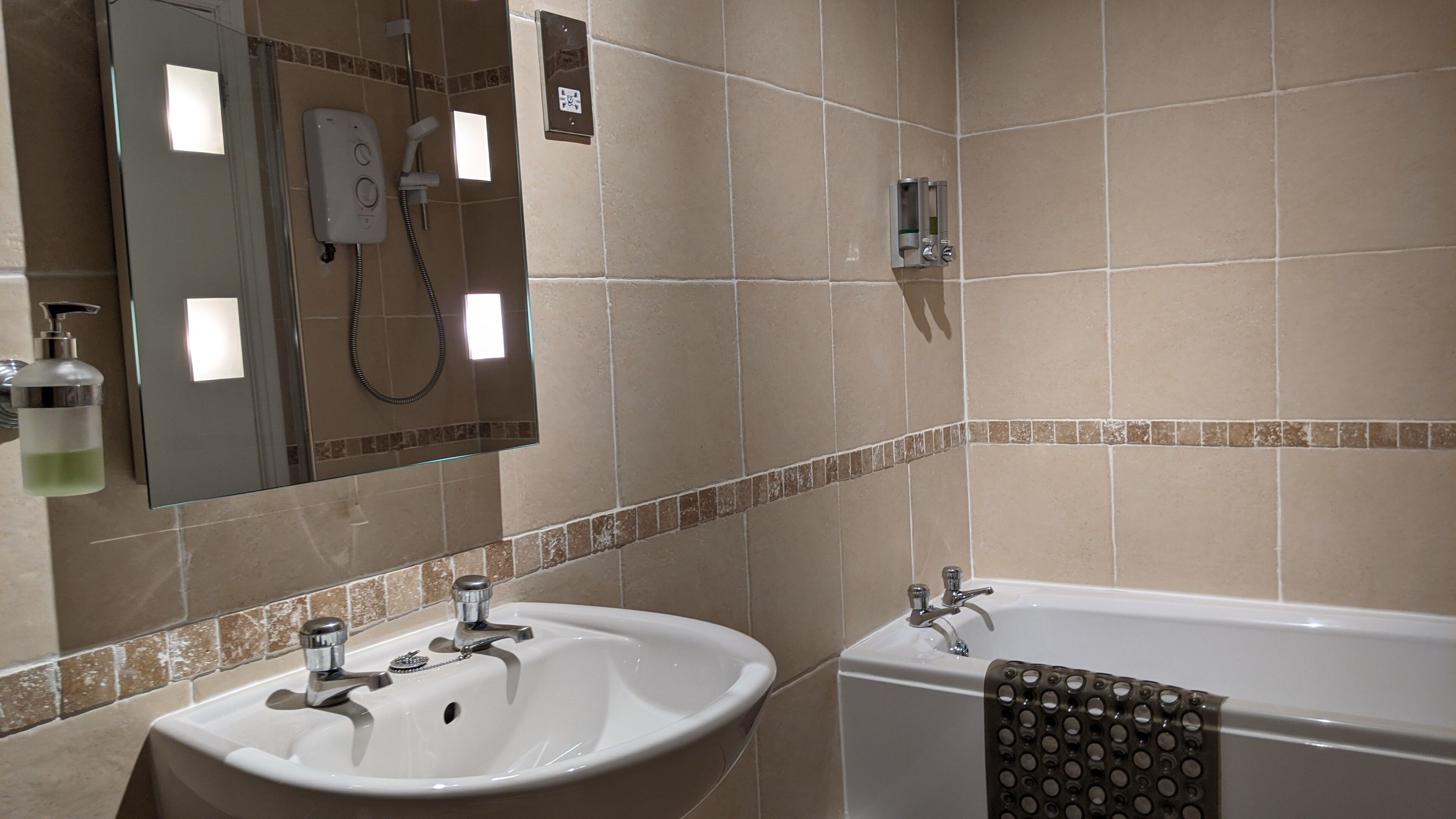 Une salle de bain avec un lavabo blanc, un miroir, une douche et une baignoire.