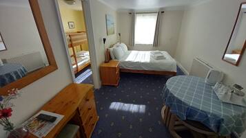 Un dormitorio con dos camas, un aparador de madera, un escritorio, un espejo y una ventana con cortinas.