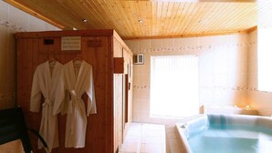 A wooden cabin with a shower area, a bathtub, and a wooden wardrobe with robes.