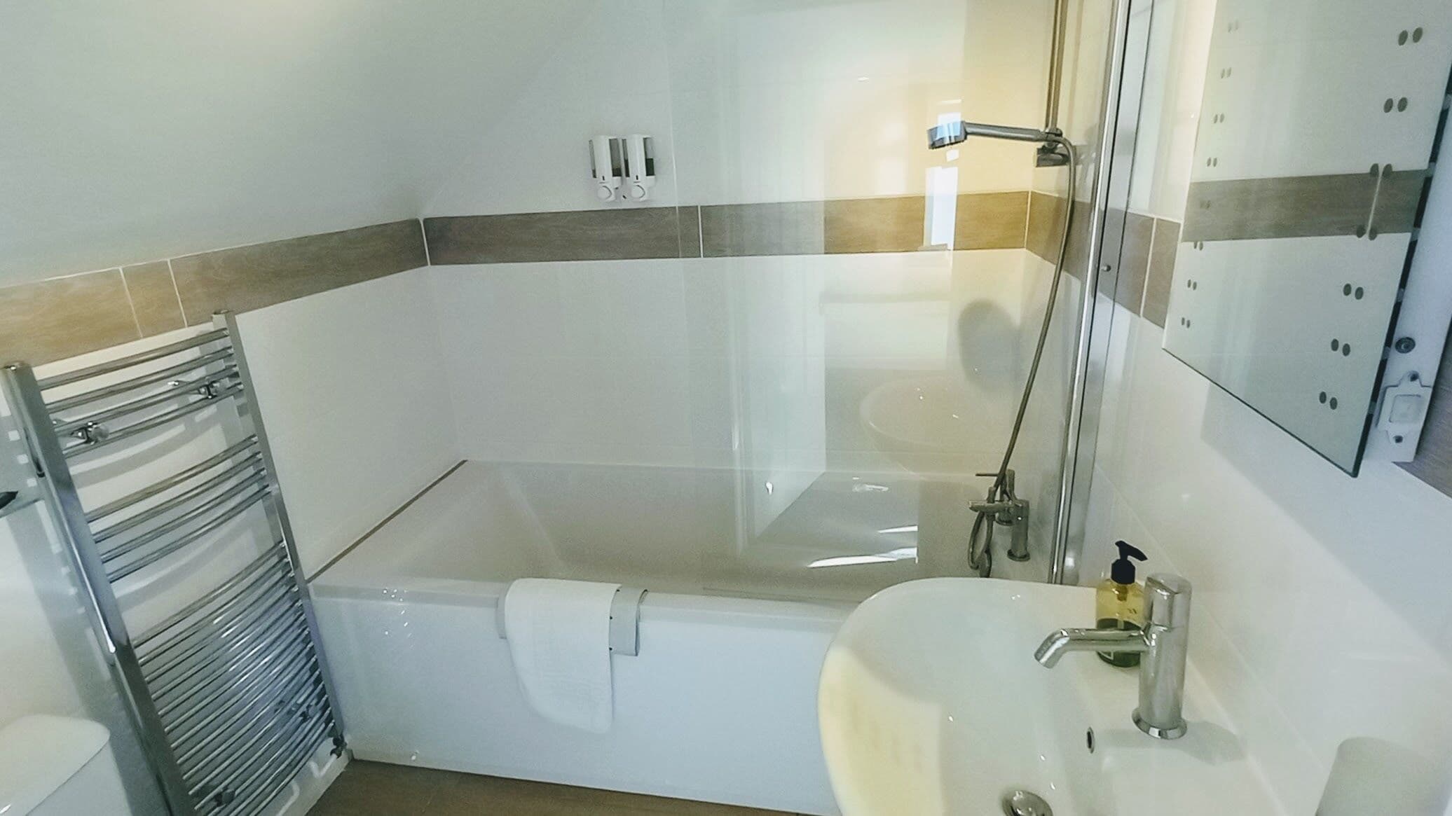 Un baño moderno con bañera, lavamanos y zona de ducha con mampara de vidrio.