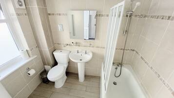 A bathroom with a toilet, sink, and shower.