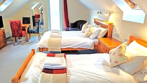 A cozy bedroom with two beds, a wooden nightstand, a chair, and a desk.