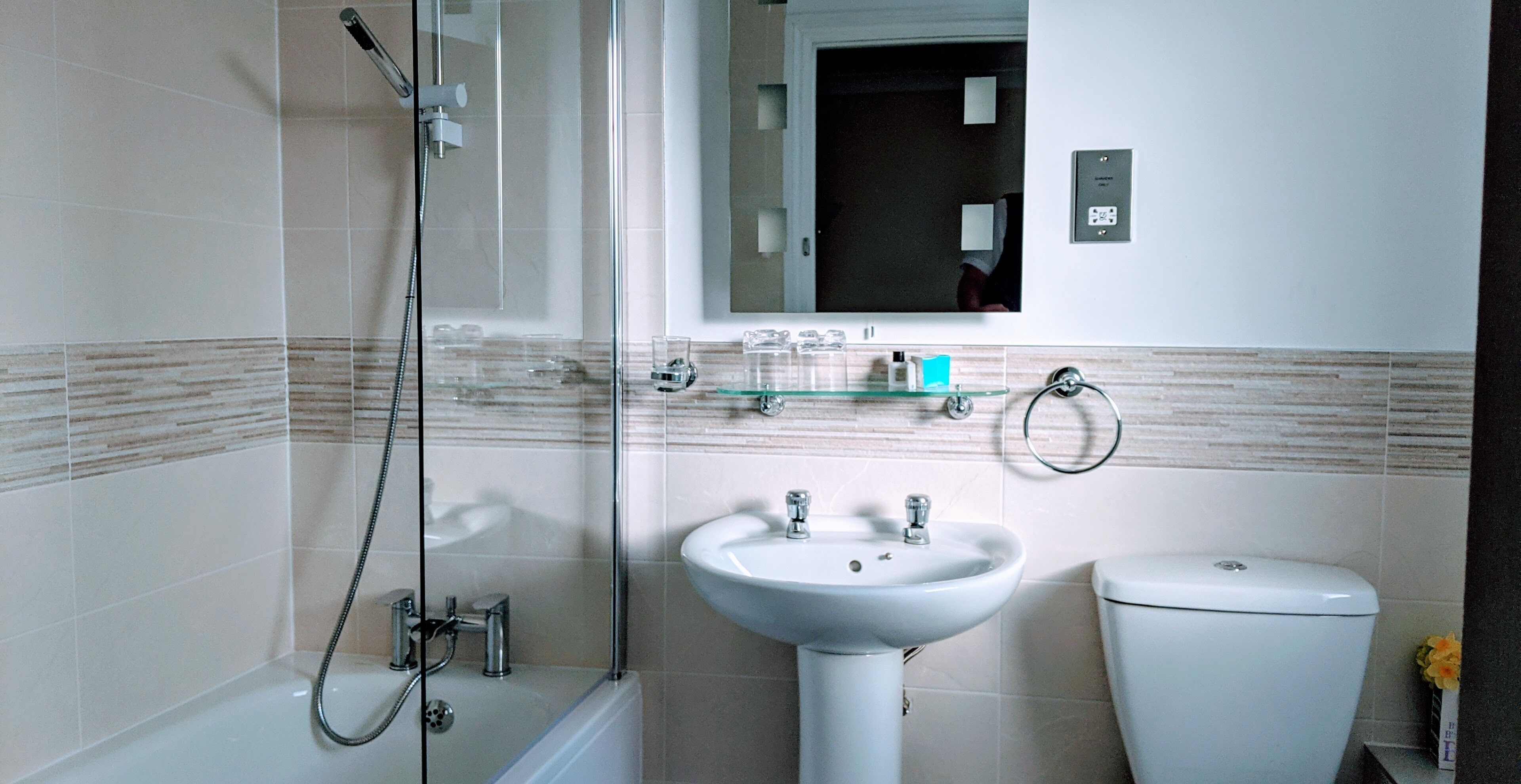 Ein modernes Badezimmer mit einer Duschkabine, einem weißen Waschbecken und einer Toilette.