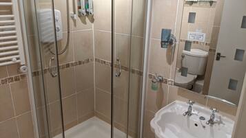 Un baño con ducha vidriada, lavamanos e inodoro.