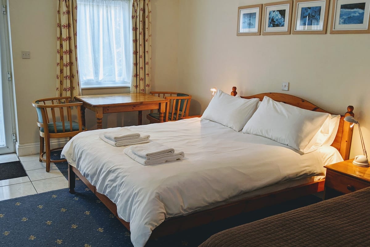 A hotel room with a bed, a desk, a chair, and a window with curtains.
