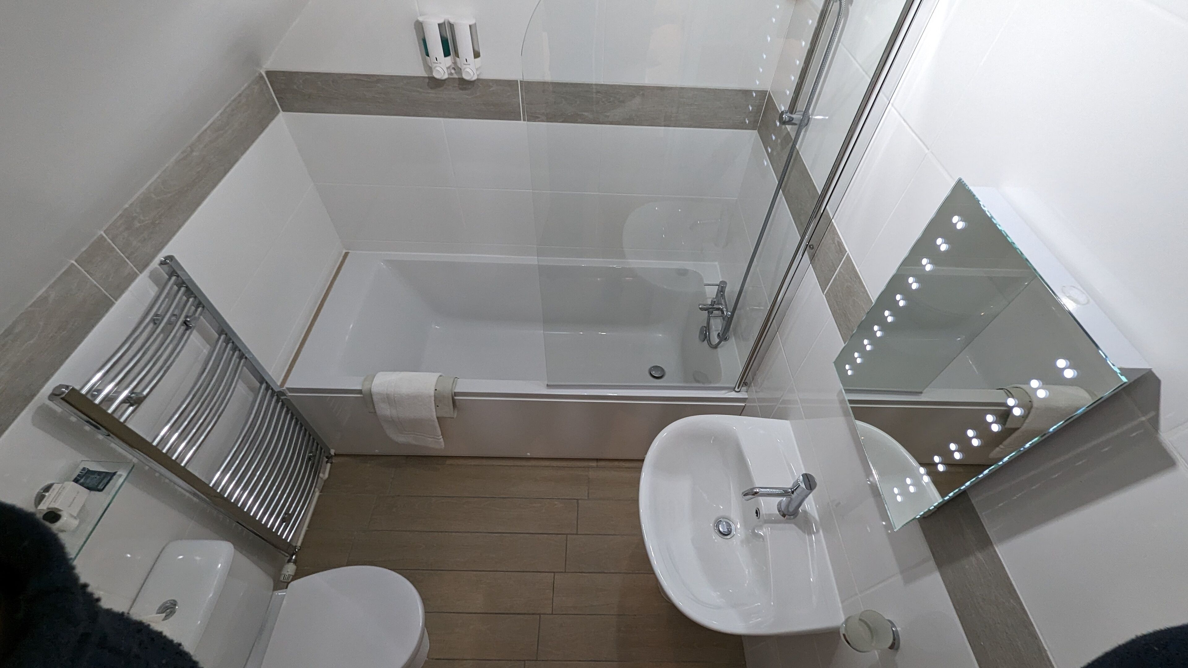 A bathroom with a bathtub, a sink, a toilet, and a mirror.
