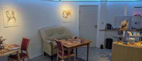A cozy room with a dining table, chairs, a sofa, and artwork on the walls.